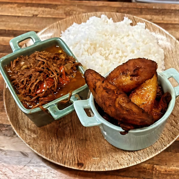 Mima's Cuban Cafe's Ropa Vieja with white rice and sweet plantains on a wooden plate.